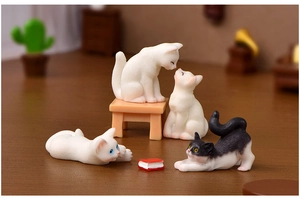 Close-up of cute miniature resin cats on tiny benches in a cozy micro-landscape setting