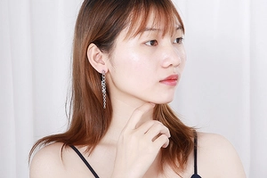 Detail of silver long chain tassel earrings featuring LOVE letter charms on a model