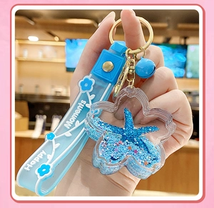 Close-up of blue starfish liquid keychain with Happy Moments strap and small bell