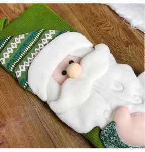 Close-up of green knit Christmas stocking featuring a 3D plush Santa Claus detail