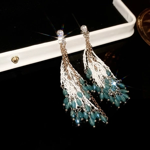 Vue macro de boucles d'oreilles à franges avec perles bleues et zircons brillants