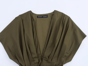 Détail du décolleté en V et plis sur une robe midi tissée de couleur olive
