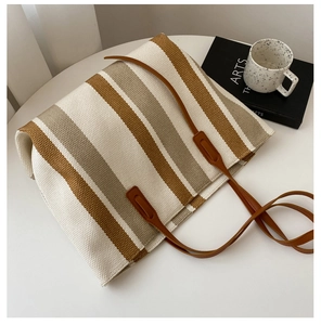 Detail showing knit texture of vertical striped tote bag with brown leather strap