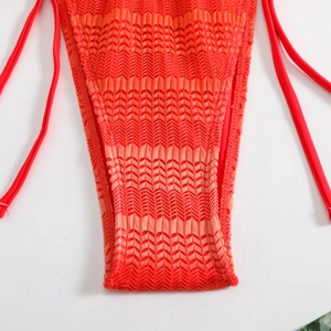 Dettaglio macro dello slip bikini rosso in maglia con trama ondulata e lacci laterali