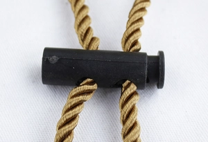 Détail macro d'un arrêt de cordon noir sur des cordons de chapeau tressés dorés
