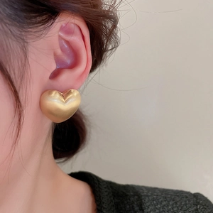 Close-up of a model wearing the matte gold 3D heart-shaped C-style stud earring