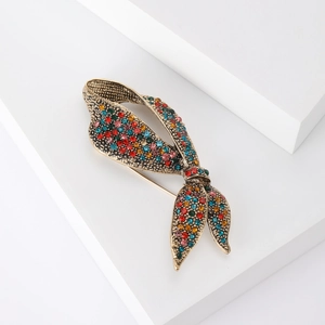 Macro view of a luxury vintage gold bow brooch inlaid with colorful crystal rhinestones