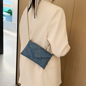 Minimalist envelope crossbody bag in washed denim blue with a fine gold chain strap