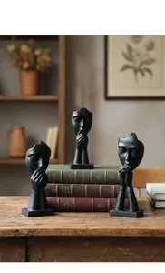 Close-up of matte black abstract human face sculptures on vintage books home decor