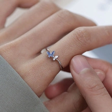 Macro shot of silver open ring with blue enamel and white zircon double butterflies