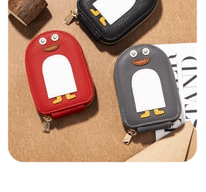 Detailed view of penguin coin purses in red, grey, and black with lychee grain leather texture