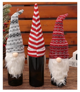 Detailed close-up of three knitted Christmas gnome wine bottle covers on a wooden table