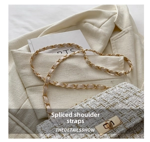 Detail of white tweed fabric texture and golden rotary metal lock on the shoulder bag