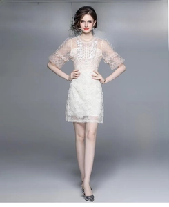 Détail de la robe en dentelle blanche avec broderie florale et sequins sur l'encolure