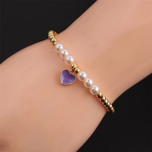 Detail of a pearl and gold bead stretch bracelet featuring a purple enamel heart charm