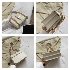 Detail view of white crocodile pattern bag with gold chain strap and accordion side design