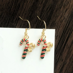Detail of Christmas candy cane earrings with red and green stripes and gold bow