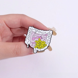 Détail du pin's émaillé en forme d'intestin avec fleur et texte Trust Your Gut