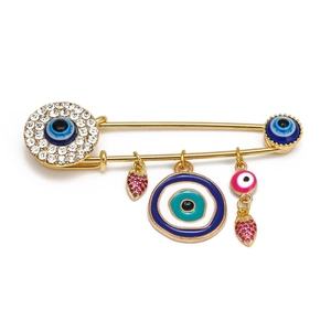 Detailed view of evil eye safety pin brooch with strawberry charms and crystal inlays