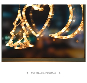 Close-up of LED Christmas window lights with warm yellow tree and moon shapes