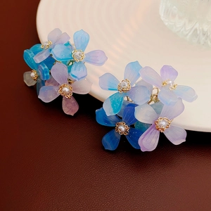 Gros plan sur les boucles d'oreilles fleurs dégradé bleu-violet avec perles blanches