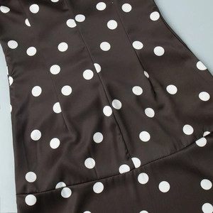 Vue détaillée de la robe noire à pois avec des fronces fines et un tissu satiné lisse