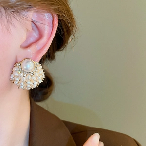 Elegant artificial pearl and crystal flower stud earrings worn by a model in a close-up view