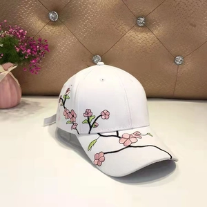 Detail of pink floral embroidery and plum blossoms on white vintage baseball cap