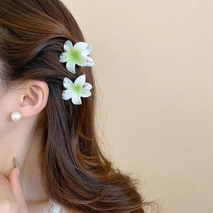 Detailed view of sweet white and green gradient sunflower hair claws in wavy brown hair