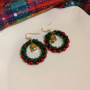 Detail shot of Christmas wreath earrings with green plush material and golden bell charms