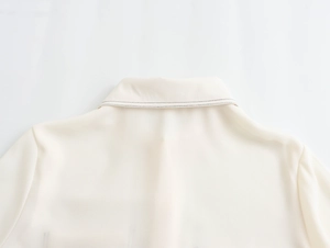 Detail of cream woven shirt collar with decorative black stitching on the neckline