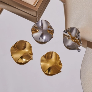 Detailaufnahme der unregelmäßigen geometrischen Ohrringe in poliertem Gold und Silber