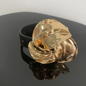 Detail van een gouden metalen bloem op zwart lederen bandje met reflecterende basis