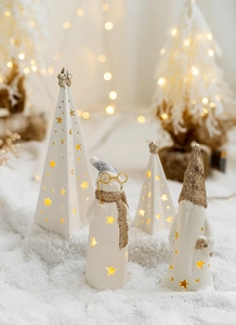 Close-up of glowing ceramic Christmas figurines with star cutouts and warm LED light