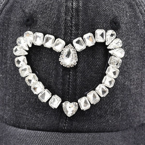 Macro view of crystal heart decoration and tassel pendant on black denim baseball cap