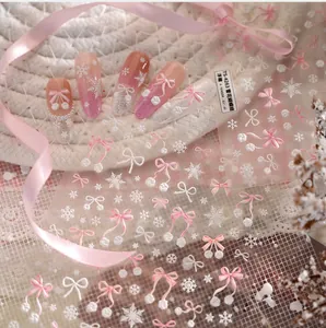 Detail of 3D embossed snowflake and pink bow nail art stickers on a winter manicure