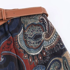 Detail eines bedruckten Midirocks mit Metallic-Streifen und braunem Kunstleder-Gürtel