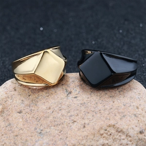 Dettaglio di anelli geometrici in oro e nero lucido posizionati su pietra naturale