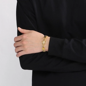 Golden double-layer Cuban link bracelet with anchor charm on a male wrist in black shirt