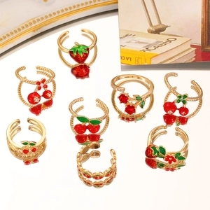 Detailed view of red strawberry and cherry adjustable gold rings with crystal accents