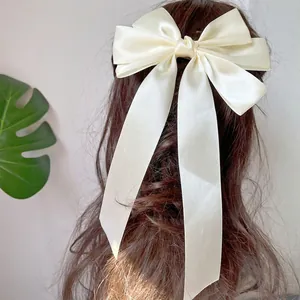 Nahaufnahme einer eleganten cremefarbenen Satin-Schleife-Haarklammer mit langen Bändern