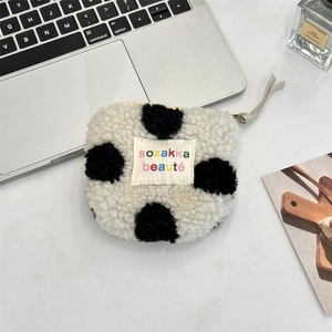 Close-up of plush cow print cosmetic pouch with sozakka beaute label and top zipper