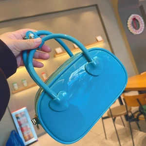 Detail of a bright blue mini PVC jelly bag with a glossy finish and top handles