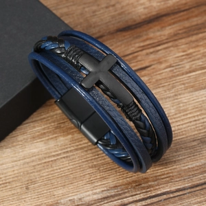 Close-up of multilayer leather bracelet with black metal cross on a rustic wooden background