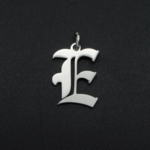 Macro shot of silver gothic letter E pendant with polished stainless steel texture