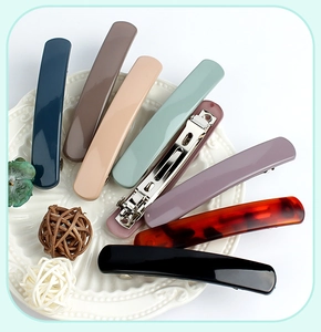 Detailed view of matte large spring hair clips in various colors on a ceramic tray