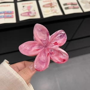 Détail d'une pince à cheveux en forme de fleur avec un motif marbre rose poli