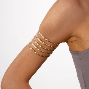 Detailed macro view of multi-layer golden wavy arm cuff with hammered metallic texture