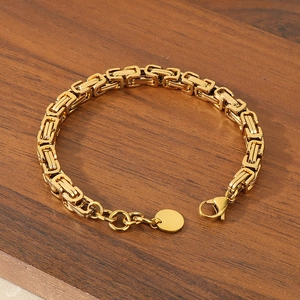 Close-up of golden box chain bracelet with lobster clasp on a dark wood background