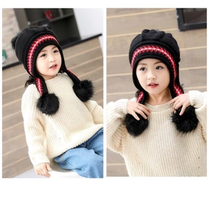 Dettaglio del cappello invernale nero bimba con pompon in pelliccia e paraorecchie